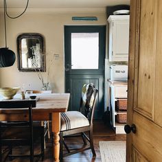 a dining room table and chairs in front of a black door with a wooden floor