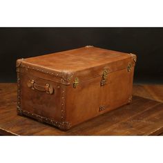 an old leather trunk sitting on top of a wooden table with riveted handles