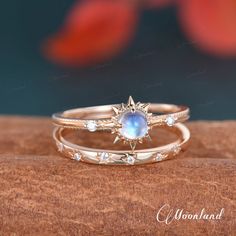 two gold rings with an oval blue stone on top, and diamond accents around the band