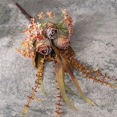 a bridal bouquet with dried flowers and leaves on a stone surface in the sun