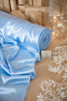 a blue blanket is laying on a table next to a vase with flowers and candles