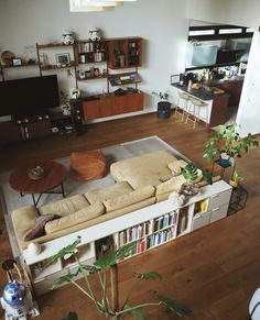 a living room filled with furniture and a book shelf on top of a hard wood floor