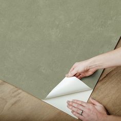 two hands on top of a piece of paper with a sheet of white paper in front of it