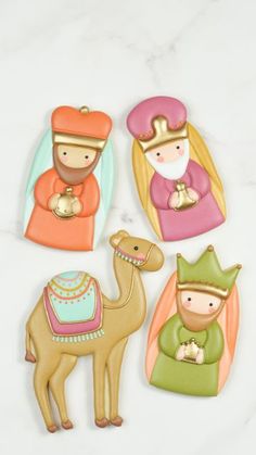 four ceramic nativity figurines in different colors and sizes on a marble surface