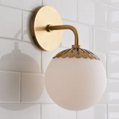 a bathroom light that is on the wall next to a tiled wall with white tiles