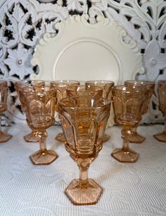 a group of glasses sitting on top of a table next to a plate and mirror