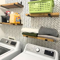 a washer and dryer sitting next to each other in a room with shelves on the wall