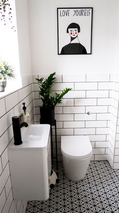 a white toilet sitting next to a bathroom sink under a framed picture on the wall