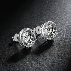 Experience the timeless elegance of a Classic 2.0 Carat Round Cut Moissanite Stud Earrings from Evani Naomi Jewelry. These high-quality earrings are simply stunning in their design and craftsmanship. Their brilliant shine is much like that of a mined diamond but comes at a significantly more affordable price. Each stud is finely handcrafted to last a lifetime, offering you a timeless piece to enjoy for years to come. They are made from a blend of 92.5% pure silver + 7.5% hypoallergenic metals an Halo Stud Earrings, Blood Diamond, Cvd Diamond, Halo Earrings, Halo Earrings Studs, Classic Engagement Rings, Moissanite Jewelry, Round Moissanite, Solid Gold Jewelry