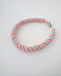 This unique beaded bangle bracelet is crafted from sead beads in 4 beautiful pastel candy colors. The round magnetic clasp is made of stainless steel and measures 0.8 cm in diameter and 1.5 cm in total lenght. It provides for a comfortable and secure way to take the bracelt on and off, while preserving a firm bangle form when wearing it. The bracelet is the ideal accessory for elegant and femine outfits.  Due to its length of 22 cm, the bracelet is better suited for larger wrists. Please measure your wrist before ordering to ensure that the bracelet will fit your size. This is a handmade item from a delicate material. Please wear with care and attention to prevent any damage. Beaded Bangles Bracelets, Crochet Beaded Bracelets, Pastel Candy, Beaded Rope, Bead Bangles, Magnetic Clasp, Candy Colors, Seed Bead, Bangle Bracelet