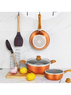 copper pots and pans on a marble countertop with wooden utensils hanging from hooks