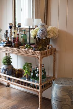 Rattan bar cart decorated with hydrangeas and touches of greenery Bar Cart Placement, Bar Cart Lamp, Grand Millennial Bar Cart, Rattan Bar Cart Styling, Drink Cart Ideas, Coastal Bar Cart, Large Bar Cart, Vintage Bar Cart Styling, Bar Cart Apartment