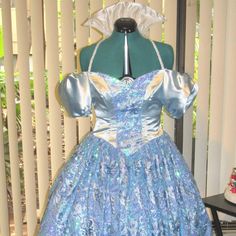 a blue dress on display in front of a white wall and wooden slatted fence