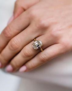 a woman's hand wearing a gold ring with an oval shaped diamond on it