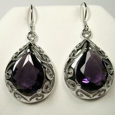 Simulated Purple Amethyst Earrings  Big Teardrop Design#E28 Custom Made This is a brand new Art Nouveau/Victorian inspired filigree sterling silver pair of teardrop simulated purple amethyst earrings. The gorgeous 12ctw purple gemstones are 16mm (5/8") by 12mm (1/2") in size each. The earrings are marked 925 for sterling silver and are 1-11/16" long by 13/16" wide. Notice the beautiful swirl like craftsmanship of the silver filigree settings. This is a well made beautiful pair of silver earrings Purple Gemstones, Purple Amethyst Earrings, Earrings Big, Antique Design, Filigree Ring, Big Earrings, Amethyst Earrings, Engraved Items, Silver Filigree