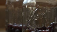 two jars filled with grapes sitting on top of a table