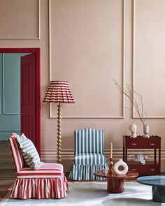 a living room filled with furniture and a lamp on top of a wooden table in front of a pink wall