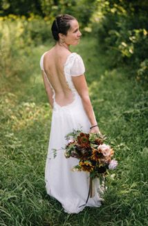 a woman in a white dress is standing in the grass with her back to the camera