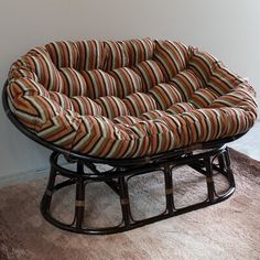 a chair that is sitting on the floor in front of a wall with a brown and orange striped seat cushion