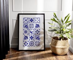 a potted plant sitting next to a framed blue and white tile pattern on the wall