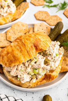 there is a sandwich with chicken salad on it and crackers next to the plate