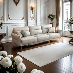 a living room filled with white furniture and flowers in vases on the floor next to windows