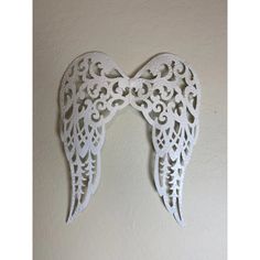 an intricately designed angel wings hang on the wall in a room with white walls