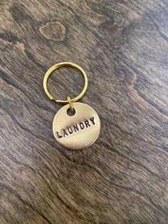 a gold keychain with the word laundry on it sitting on a wooden surface