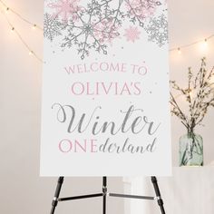 a welcome sign is displayed in front of a white wall with pink and gray snowflakes