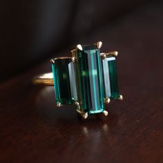 The showstopper. Three lush luxurious AA green tourmalines are set in slim claw settings and sit atop a classic round band. Classic with a twist, this art deco inspired piece makes a fantastic statement ring or a wedding piece. Spiritually, green tourmaline carries the essence of the earth and her plant kingdom. It's conducive to healing, happiness, and setting a clear & grounded direction for the future. The Details: One of a kind! Solid recycled 14k yellow gold. 9.71 total carats of AA Brazili Plant Kingdom, Art Deco Inspired, Green Tourmaline, Of The Earth, Statement Ring, The Earth, Tourmaline, A Wedding, Statement Rings