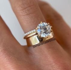 a woman's hand with a diamond ring on top of her finger and an engagement band