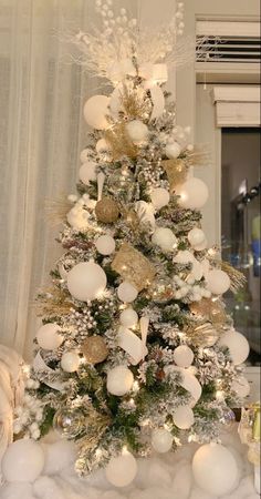 a white christmas tree with gold and silver ornaments