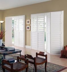 a living room filled with furniture and windows covered in white shuttered shades on the doors