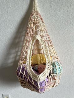 a hammock hanging on the wall with balls of yarn in it