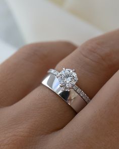 a woman's hand with a diamond ring on top of her finger and the engagement band