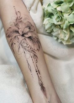 a woman's leg with a flower tattoo on it and an arrow in the middle