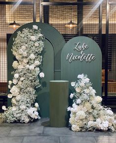 white flowers and greenery on display in front of an entrance