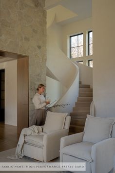 a woman sitting on a chair in front of a spiral stair case next to a couch