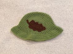 a crocheted green hat with a brown bear on it