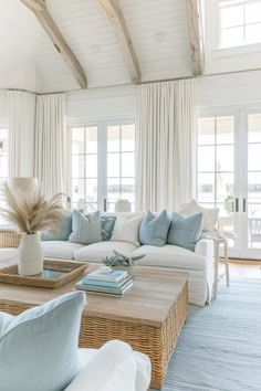 a living room filled with white furniture and lots of blue pillows on top of it