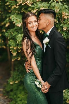 a man in a suit and tie kissing a woman in a green dress with flowers on her lap