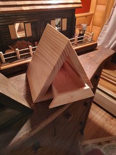 a wooden box sitting on top of a table next to a doll's house