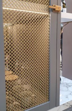 a close up of a metal door on a marble counter with wine bottles in the background