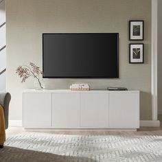 a flat screen tv sitting on top of a white cabinet