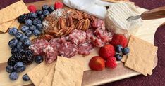 cheese, fruit and crackers on a cutting board