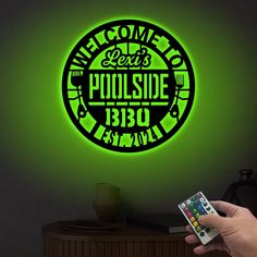 a person holding a remote control in front of a neon sign that reads welcome to paradise bbq