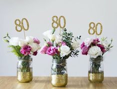 three mason jars with flowers and gold numbers