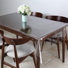 a glass table with chairs around it and a vase filled with flowers on the table