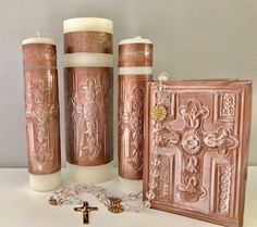 three candles are next to a cross and a card holder with a chain on it