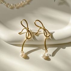 - BOWE -  Grace your ears with these super chic golden ribbon earrings demonstrating the unique beauty of intertwined ribbons. This is bold and chic enough for occasions when you wish to make a decently chic statement. Plus it's sooo unique and perfect for this holiday season! ✨ //Materials// 14k Gold Filled Ribbon & Gold Vermeil Post (Gold on silver) Freshwater natural pearls //Dimension// Ribbon length: 2 inch Ribbon width: 1 inch Pearl Drop: 0.5 inch **Feel free to ask me anything if you have Elegant Rose Gold Earrings With Bow, Elegant Rose Gold Bow Earrings, Yellow Gold Bow Earrings For Wedding, Elegant Gold Jewelry With Ribbon, Elegant Yellow Gold Jewelry With Ribbon, Gold Dainty Pearl Earrings For Party, Dainty Gold Pearl Earrings For Party, Gold Ribbon Earrings For Party, Gold Pearl Earrings With Ear Wire For Party